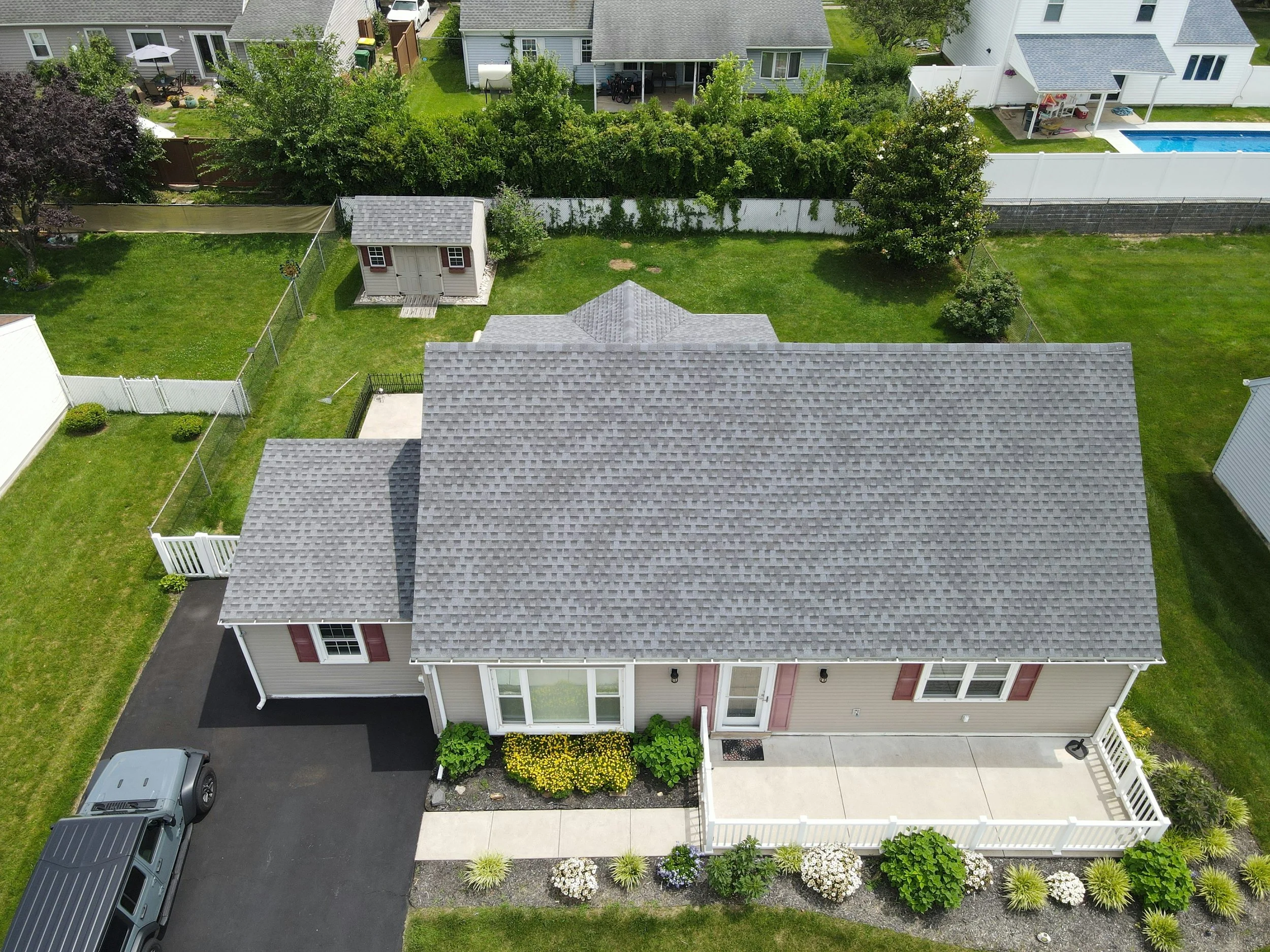 An aerial view of a suburban backyard with a gray house, a small shed, green lawns in New Hampshire. House washing and Roof washing located in Southern New Hampshire and Massachussetts!