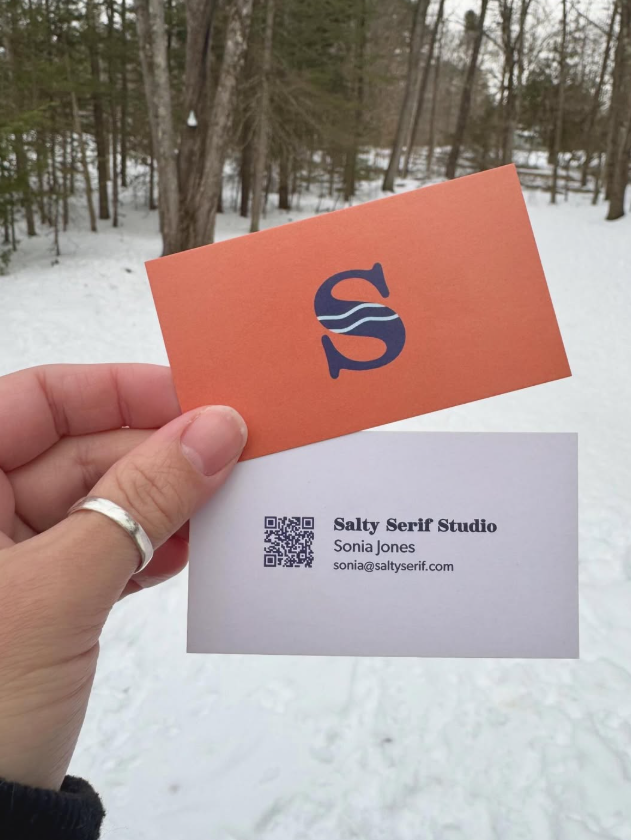 Hand holding a Salty Serif Studio business card against a snowy landscape.
