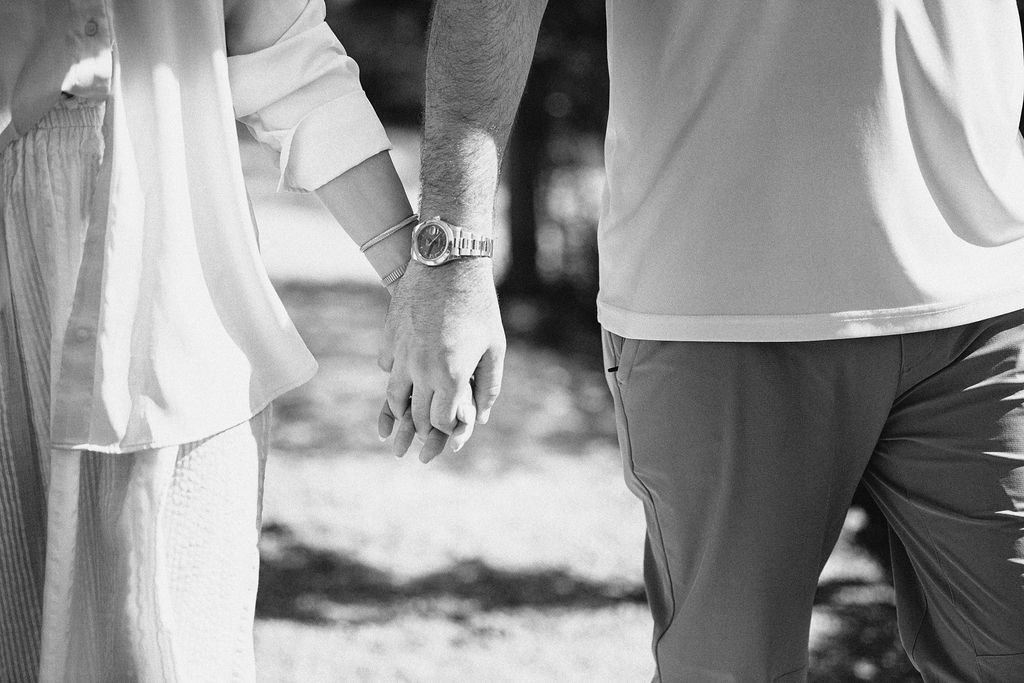 Two people holding hands outdoors in black and white