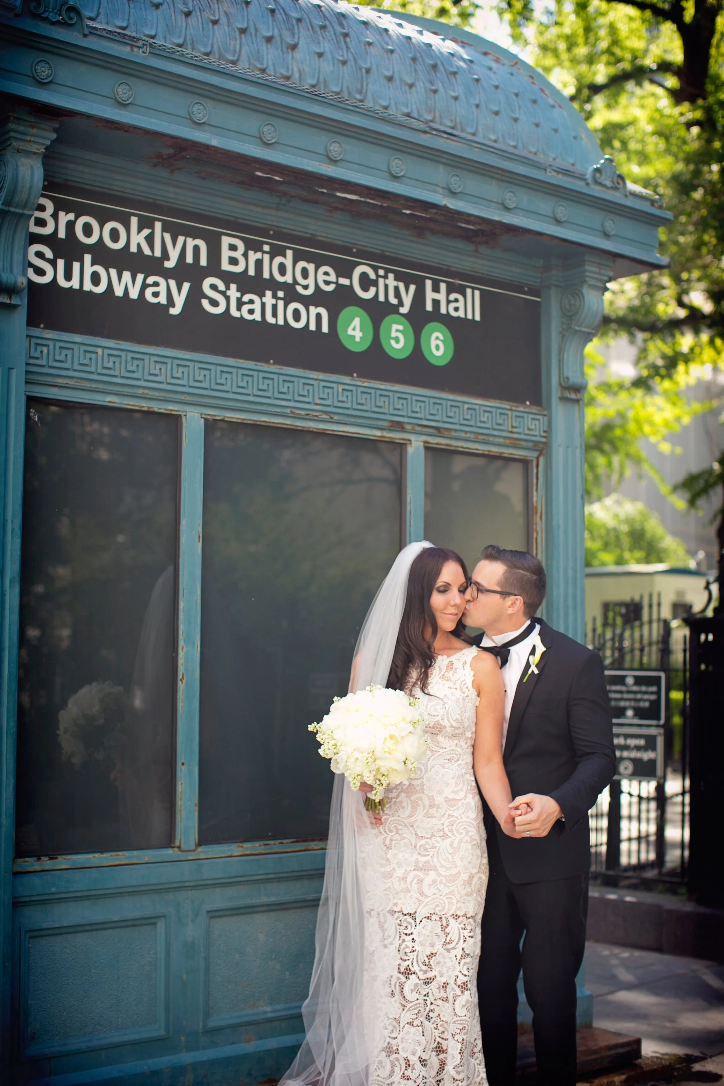 A newlywed couple kissing in front of a Brooklyn subway station entrance