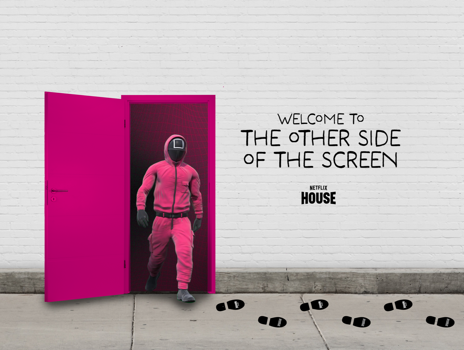 A guard from the Netflix series, Squid Game, is walking through an open pink door. The door is attached to a white brick wall, and footprints are leading toward it. Text on the wall says "Welcome to the other side of the screen" and "Netflix House."