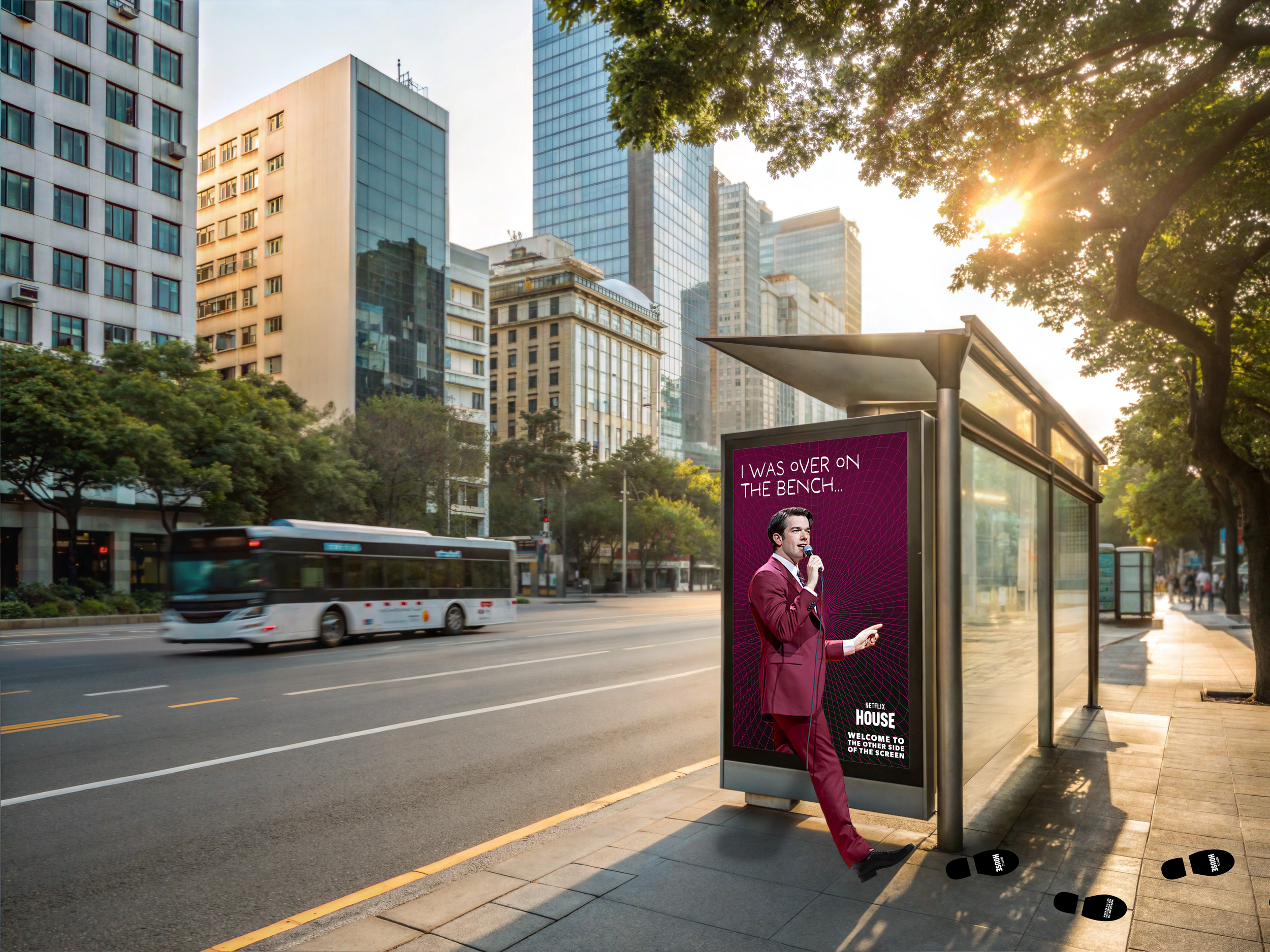 John Mulaney 'climbing out' of an urban bus stop advertisement. Reads "Welcome to the other side of the screen" and the Netflix House logo.
