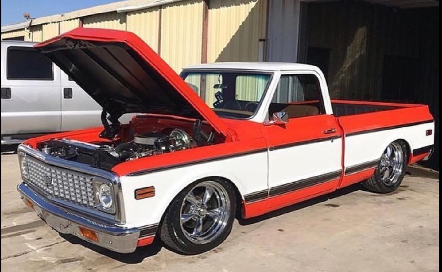 Orange and white Chevy C10 with hood popped open