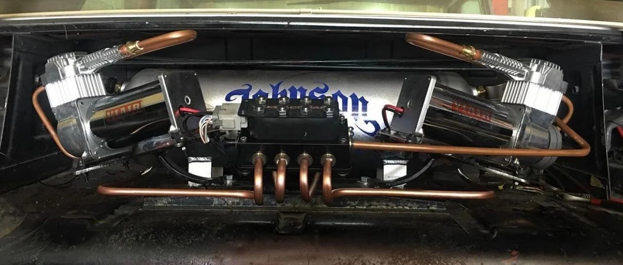 Close-up of a mechanical system with copper pipes, metallic cylinders, and wires inside a black enclosure.