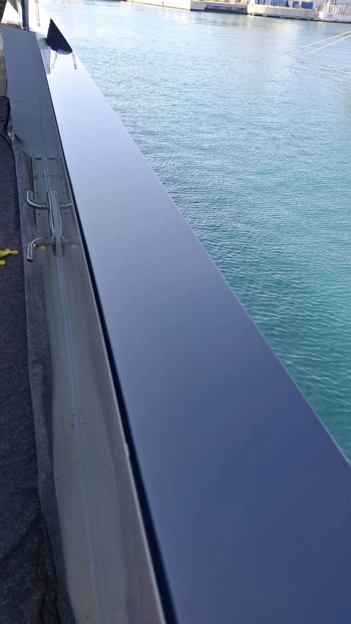 Close-up view of a boat railing with water and docked boats in the background