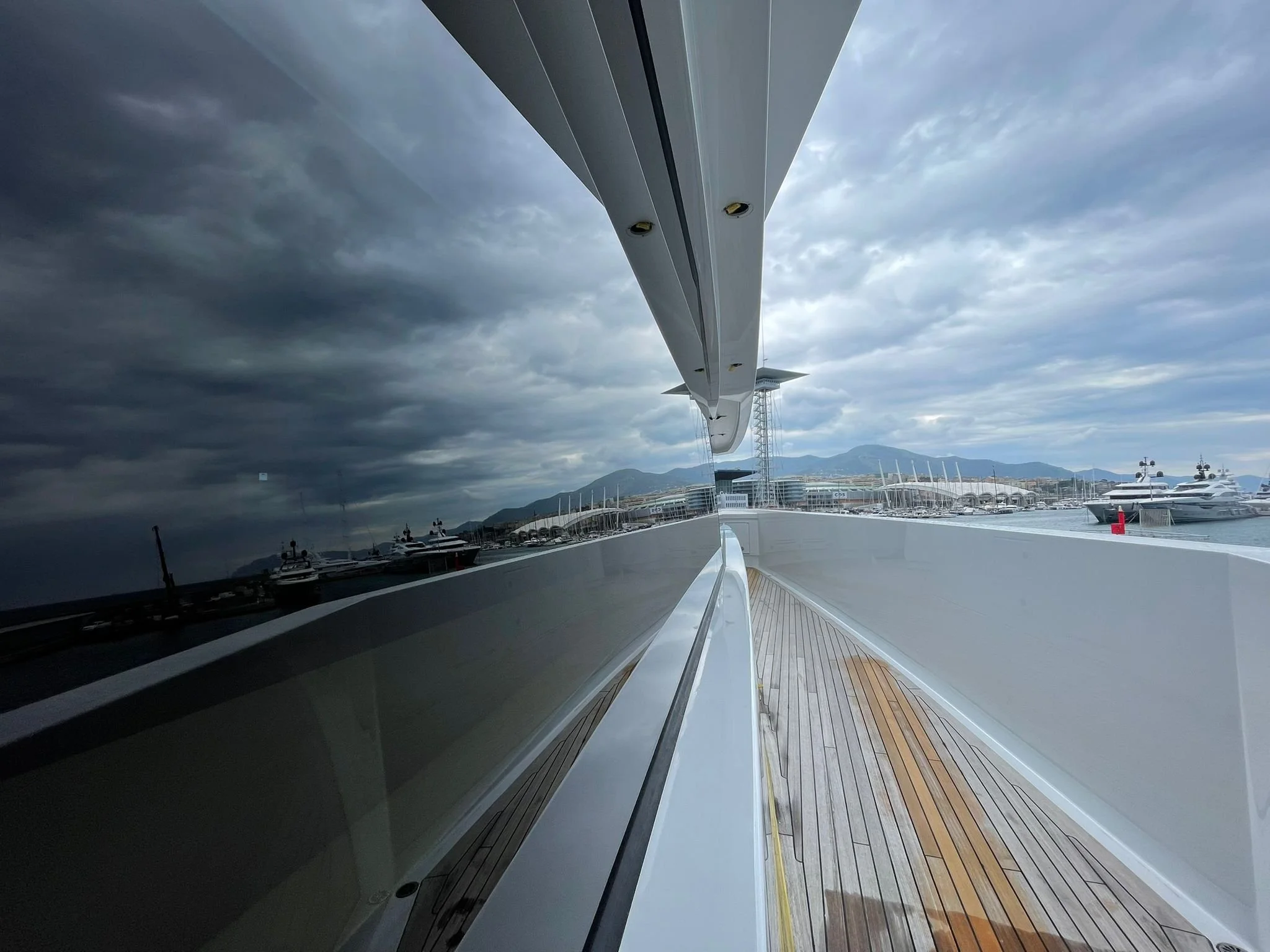 Two side-by-side photographs of yacht masts viewed through reflective boat windows at a marina on a clear, sunny day.