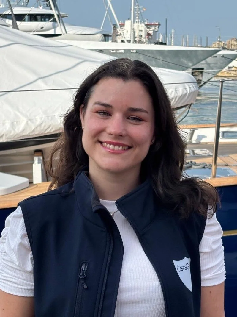 Young woman smiling, standing near docked boats and yachts at a marina