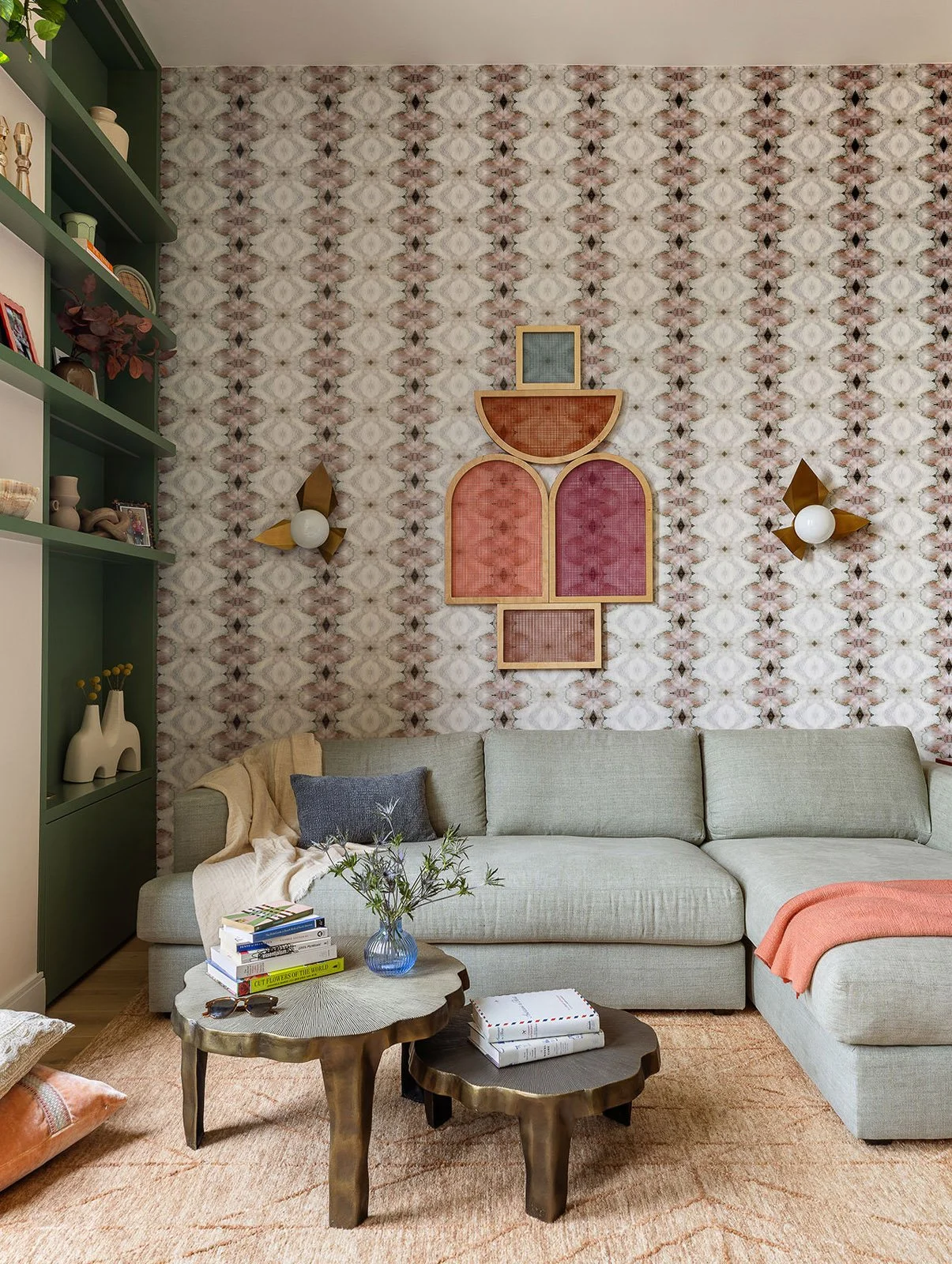 Character-filled living room with patterned wall, sculptural art and rustic wood tables styled with books and flowers