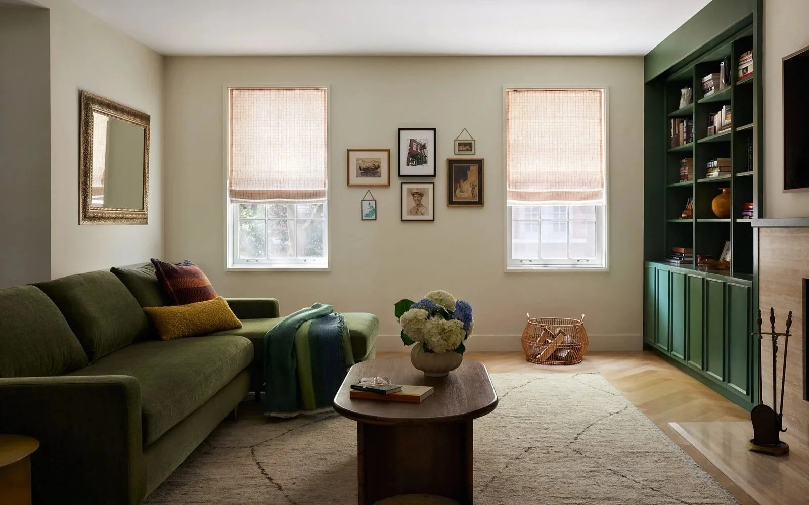 Light-filled living room with green sofa, gallery wall and green built-ins creating a modern, inviting space