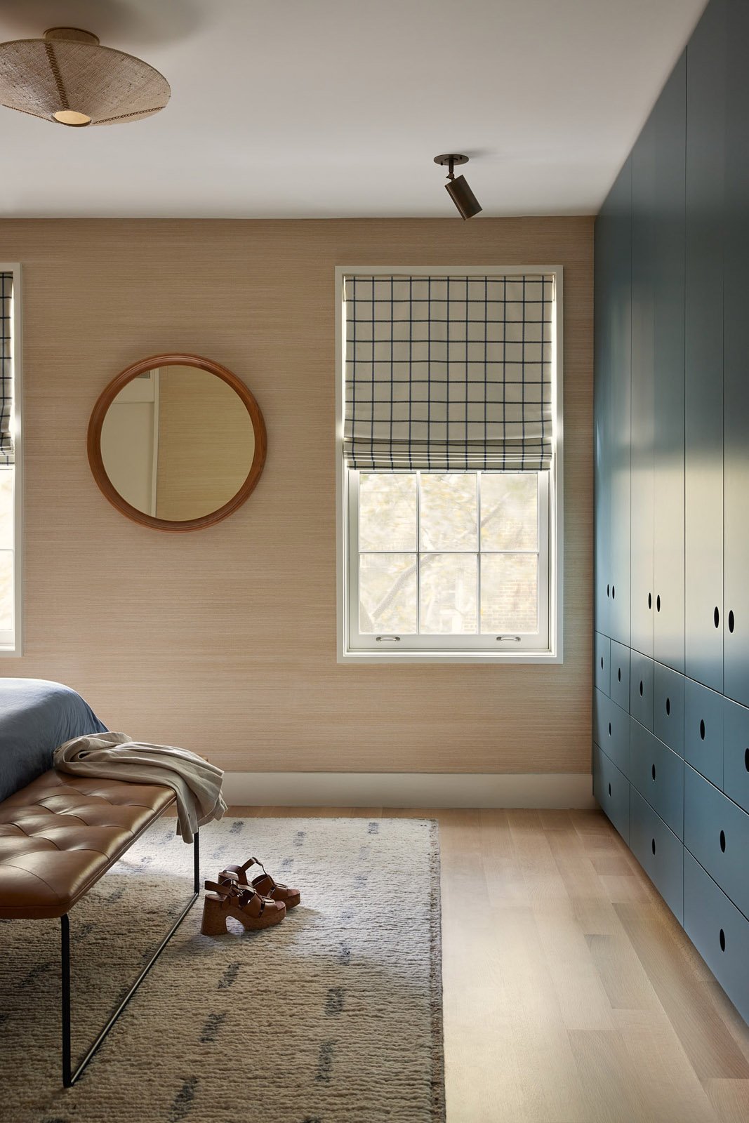 Light-filled bedroom view with blue built-in wardrobes, grid roman shade and soft textures creating a modern, serene feel