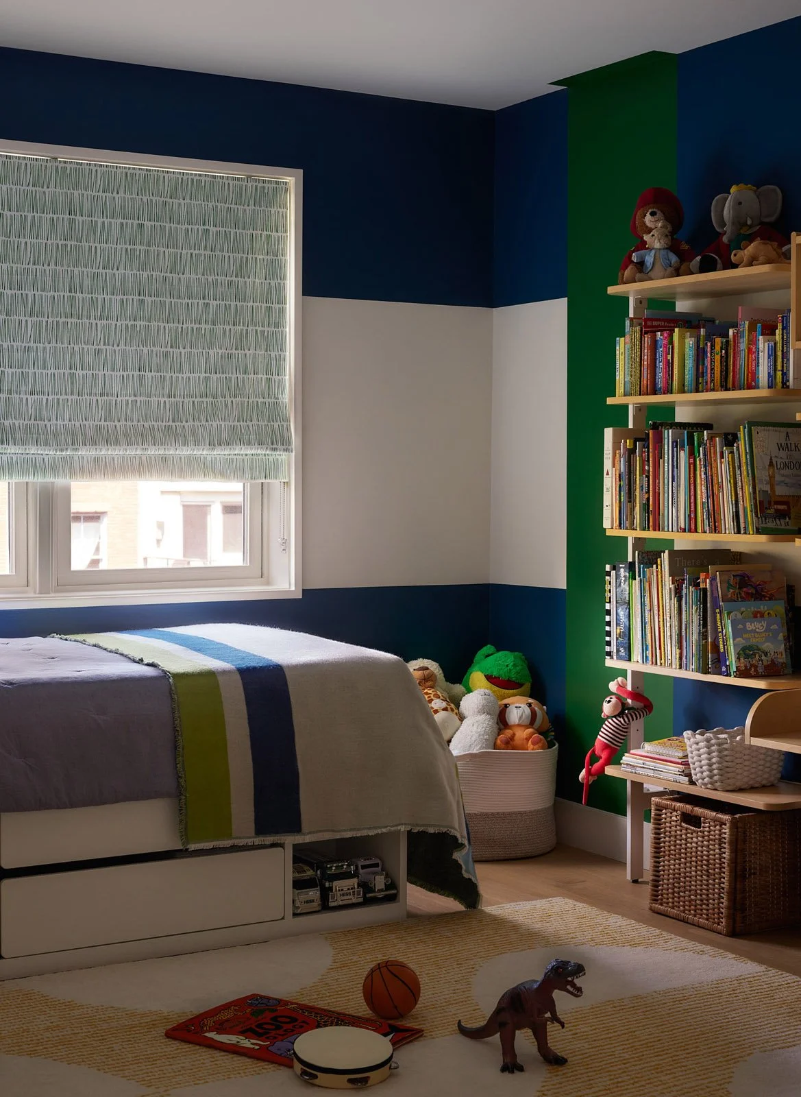 Kids’ bedroom with bold stripe walls in navy and green, playful decor and built-in storage for a bright, modern family space