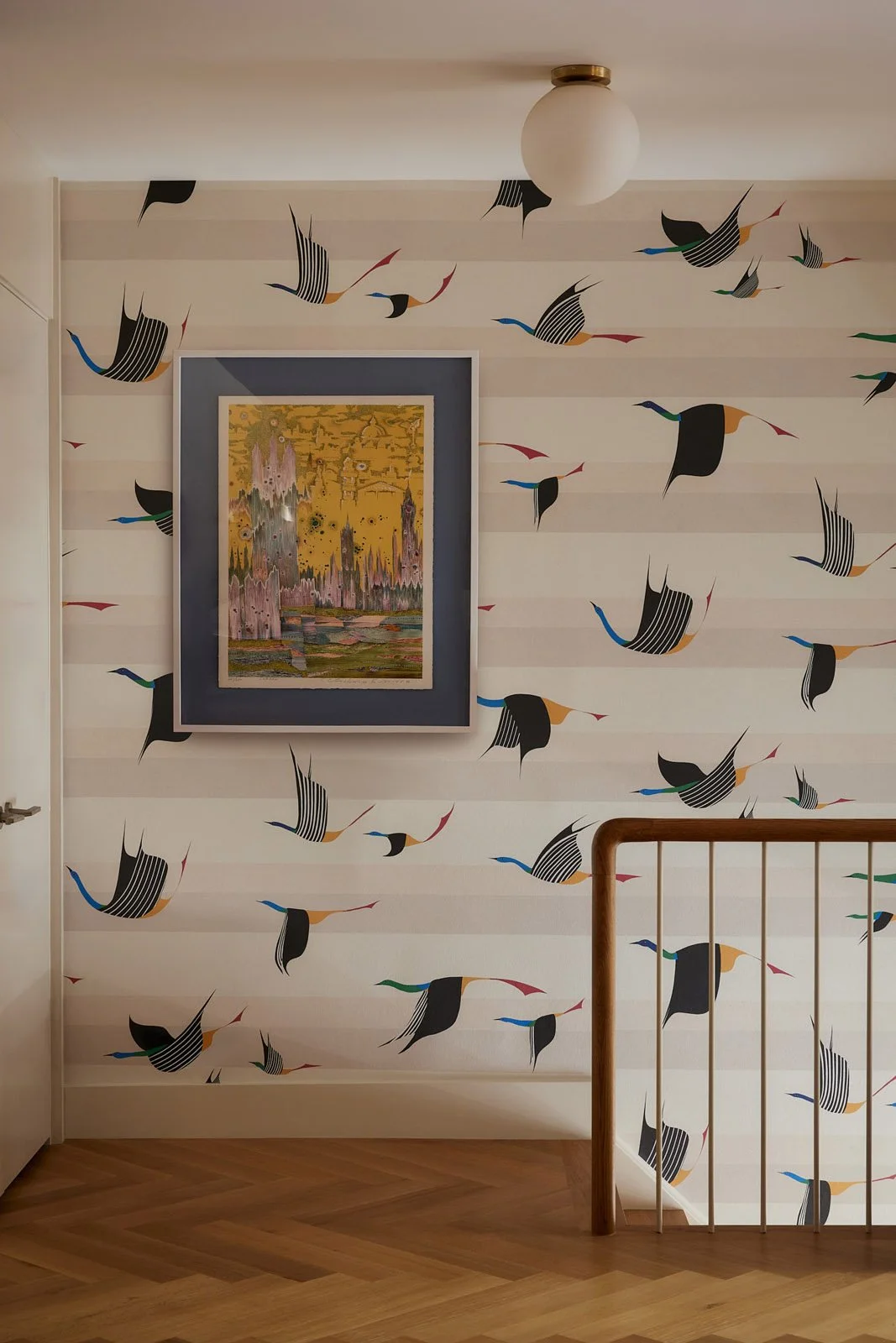 Hallway with bold bird-patterned wallpaper and framed art adding playful, modern character to this NYC brownstone