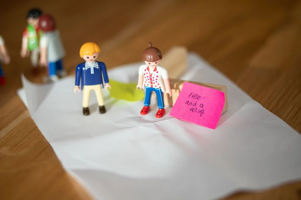 Accessing the unconscious thinking with constellation thinking and Playmobil figures on paper with pink sticky note