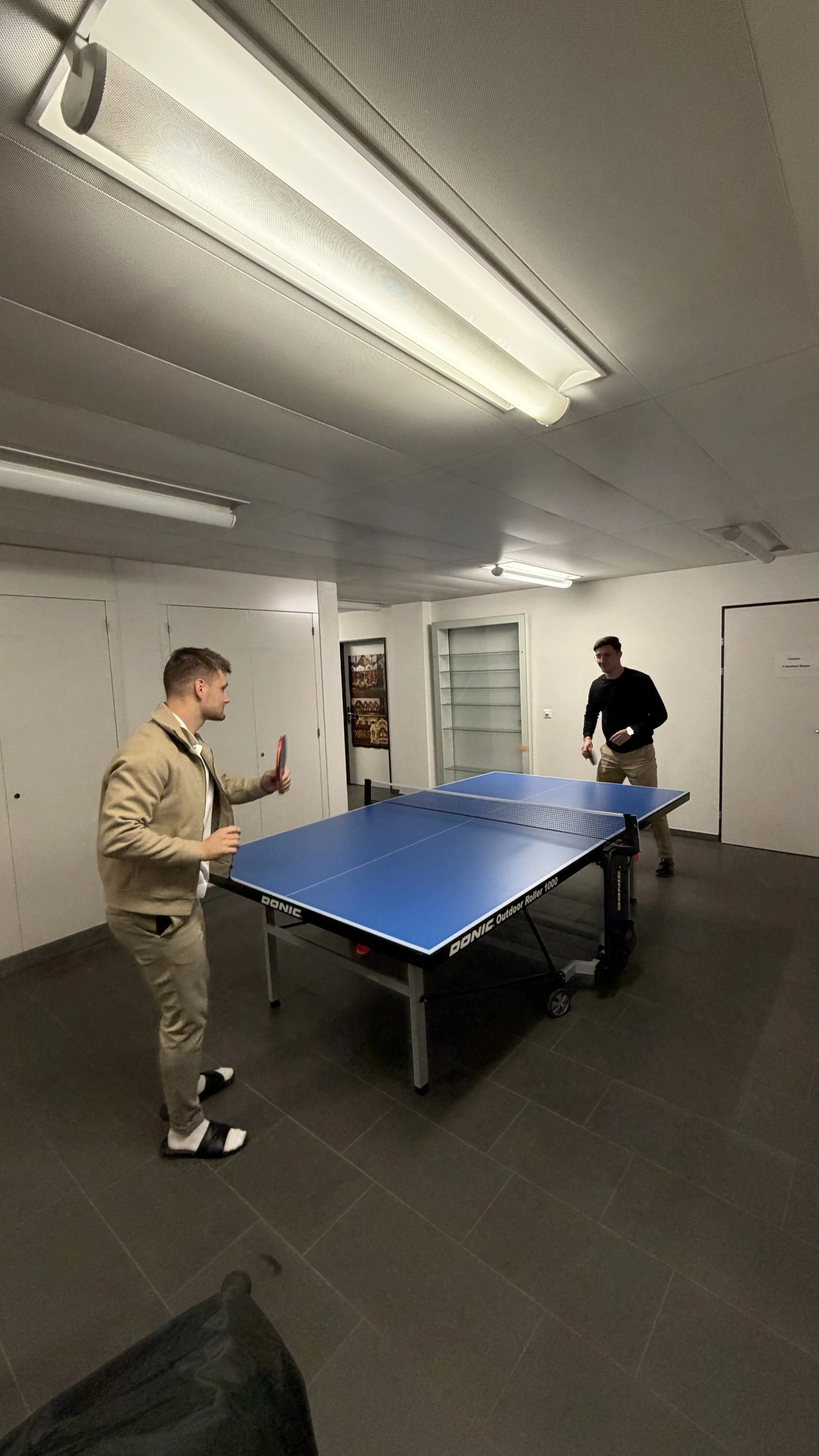 Zwei Männer spielen Tischtennis in einem untersuchten Raum.