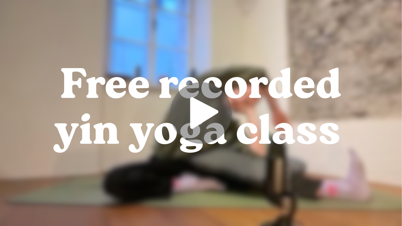 A person practicing yoga in a room with a brick wall and a window, sitting on a yoga mat, wearing athletic clothing.