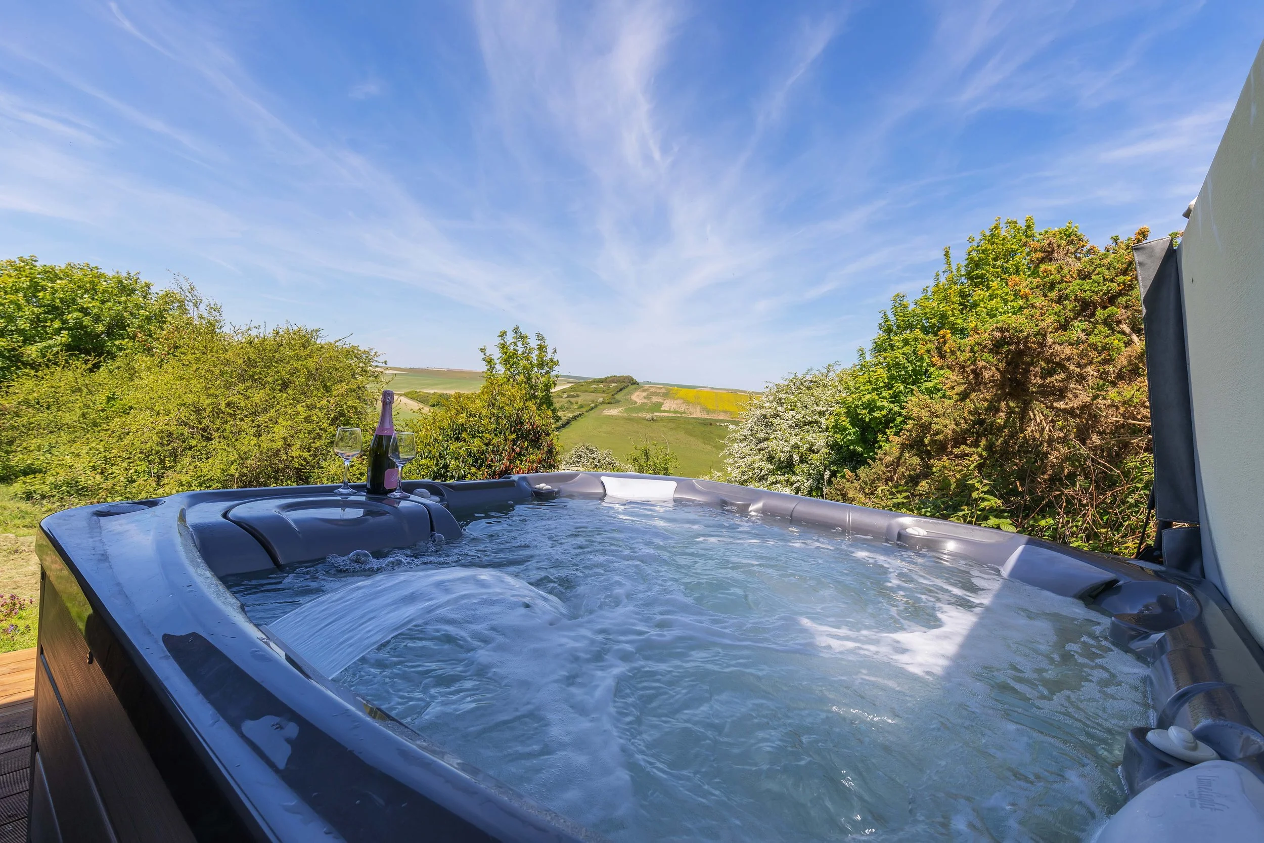 A private deck with a hot tub and shaded seating, overlooking stunning rolling fields, ideal for relaxation during retreats.
