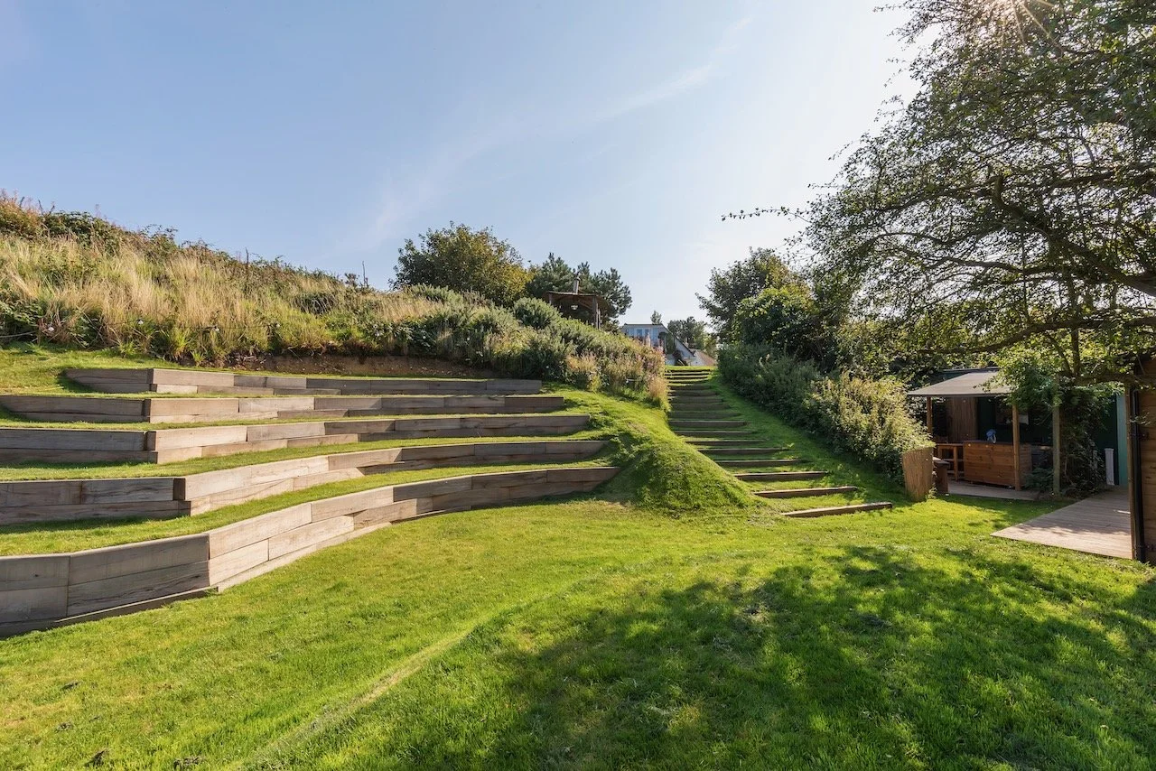 Outdoor amphitheater with layered seating and vibrant greenery, a serene spot for group activities at music and wellness retreats.