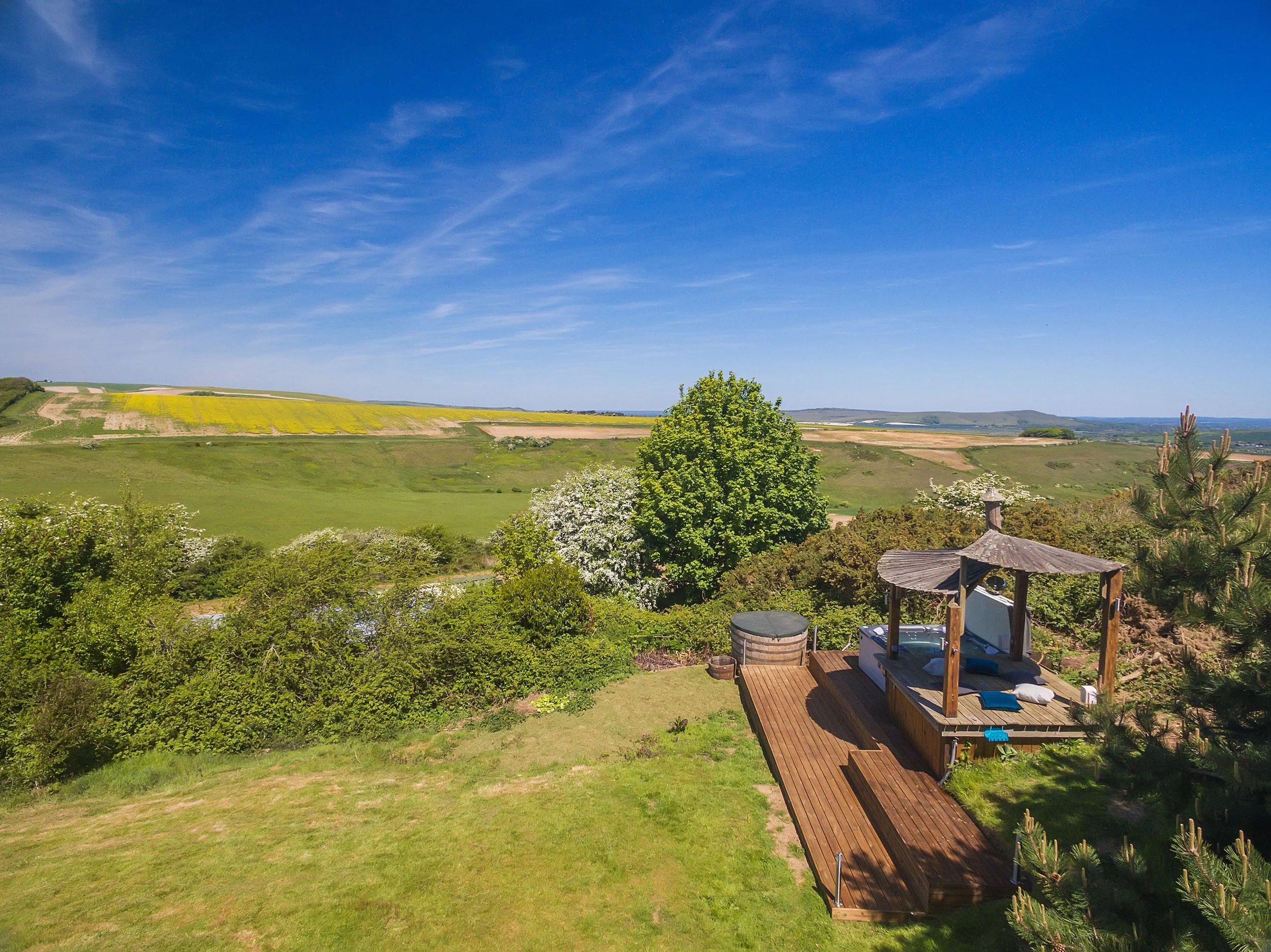 A tranquil hot tub on a wooden deck overlooking breathtaking countryside, ideal for rejuvenation at a UK retreat accommodation.