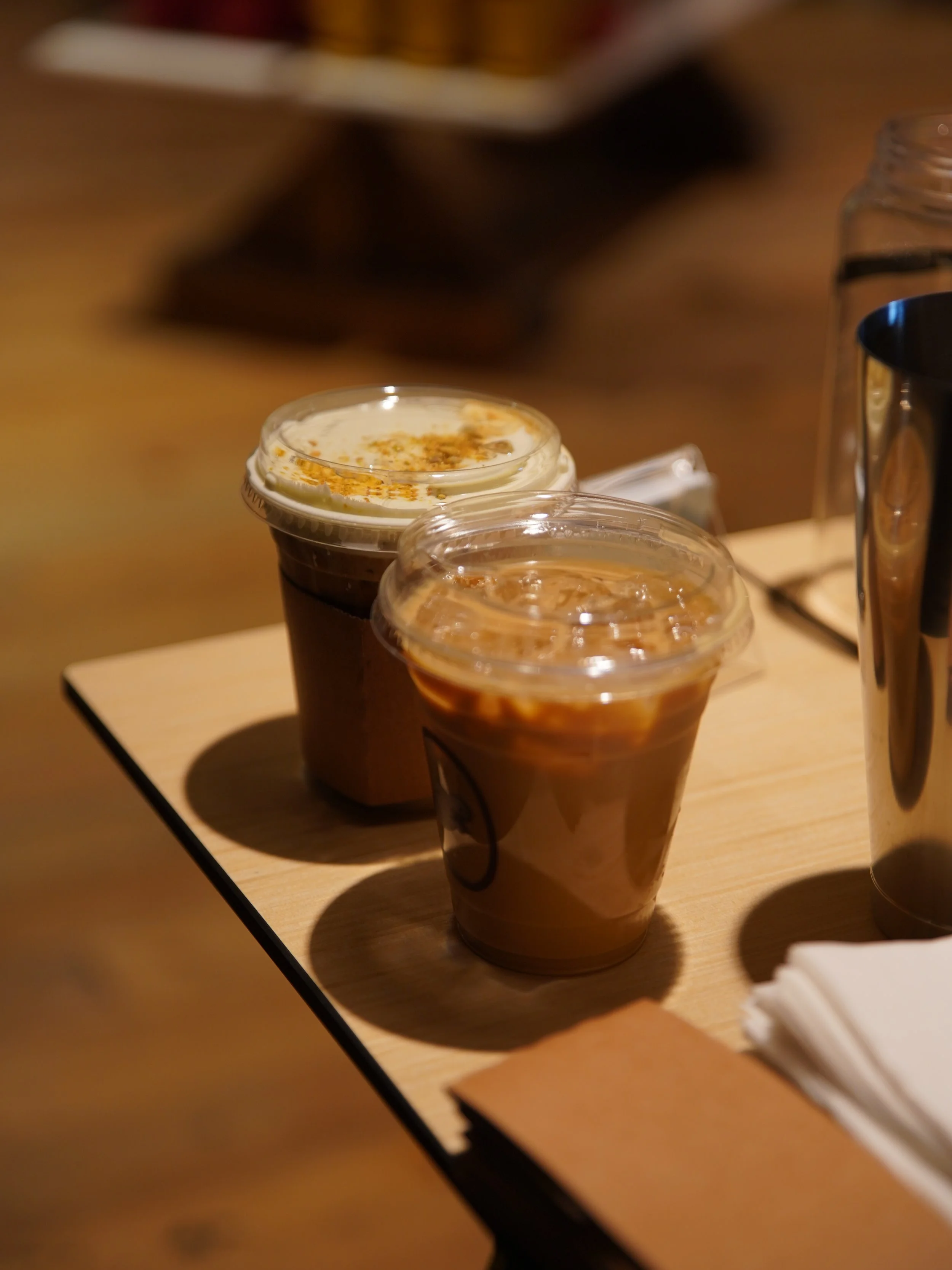 La Marzocco GS3 espresso machine, a vase with white tulips, plastic cups, jars, and assorted drink cups on a coffee cart at a corporate event office building in Pasadena, CA.