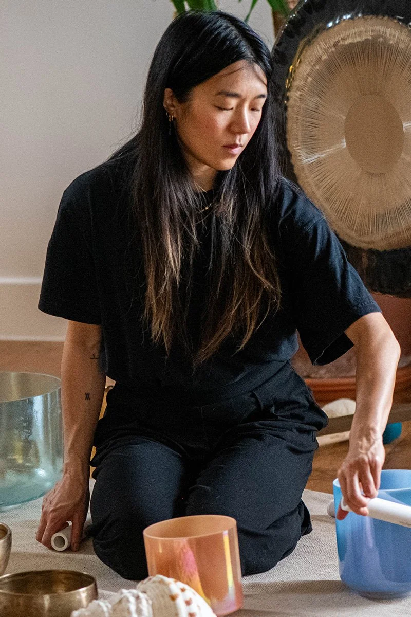 Woman with long hair leans over gongs at a gong bath