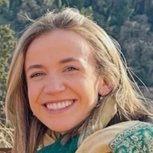 A woman with blonde hair smiling in the outdoors