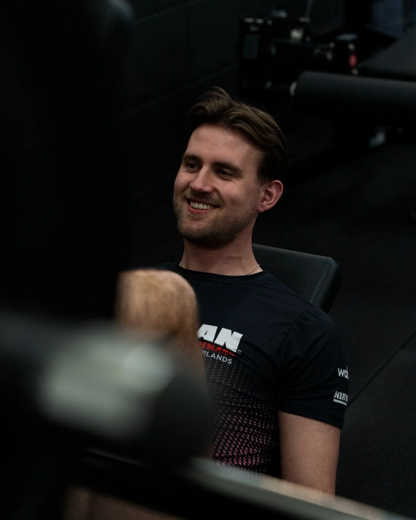 Man in een sportschool die met dumbbells aan het trainen is, omringd door gewichten en fitnessapparatuur.