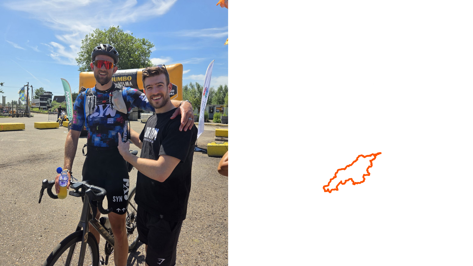 Twee mannen die samen met een fiets staan, één met een helm en sportkleding en de ander in een T-shirt, op een zonnige dag met blauwe lucht, bomen en een evenementinfrastructuur op de achtergrond.