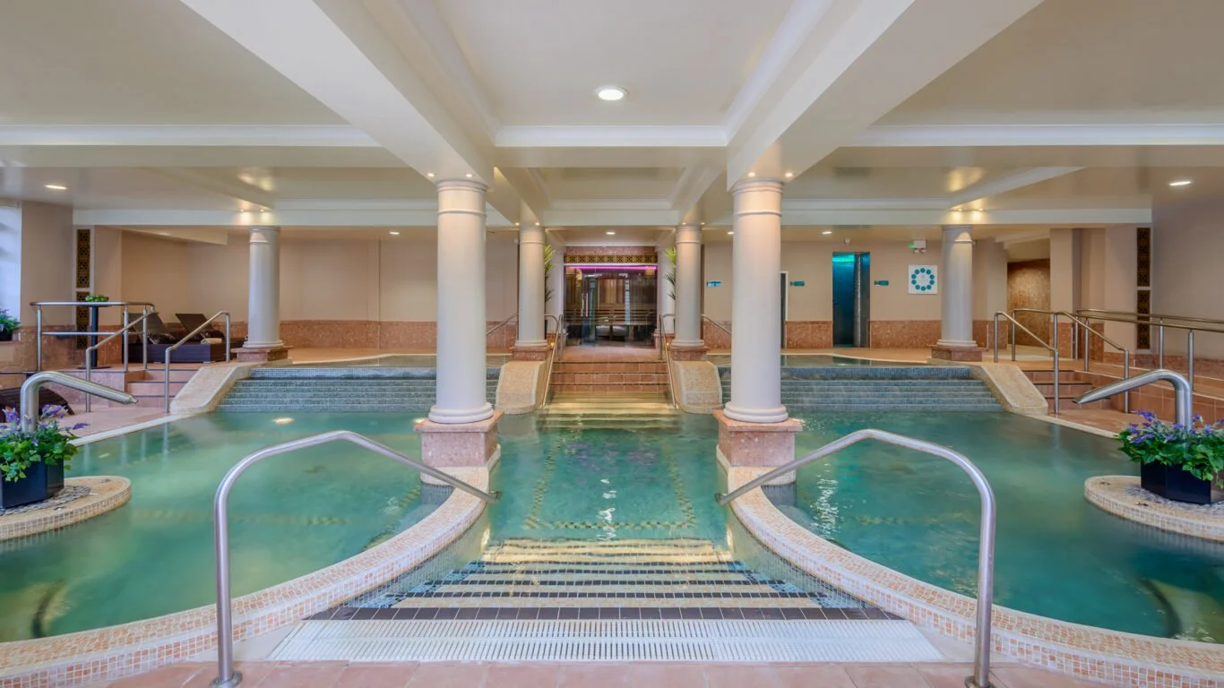 Indoor spa with multiple hot tubs, steps, and columns in a luxury hotel