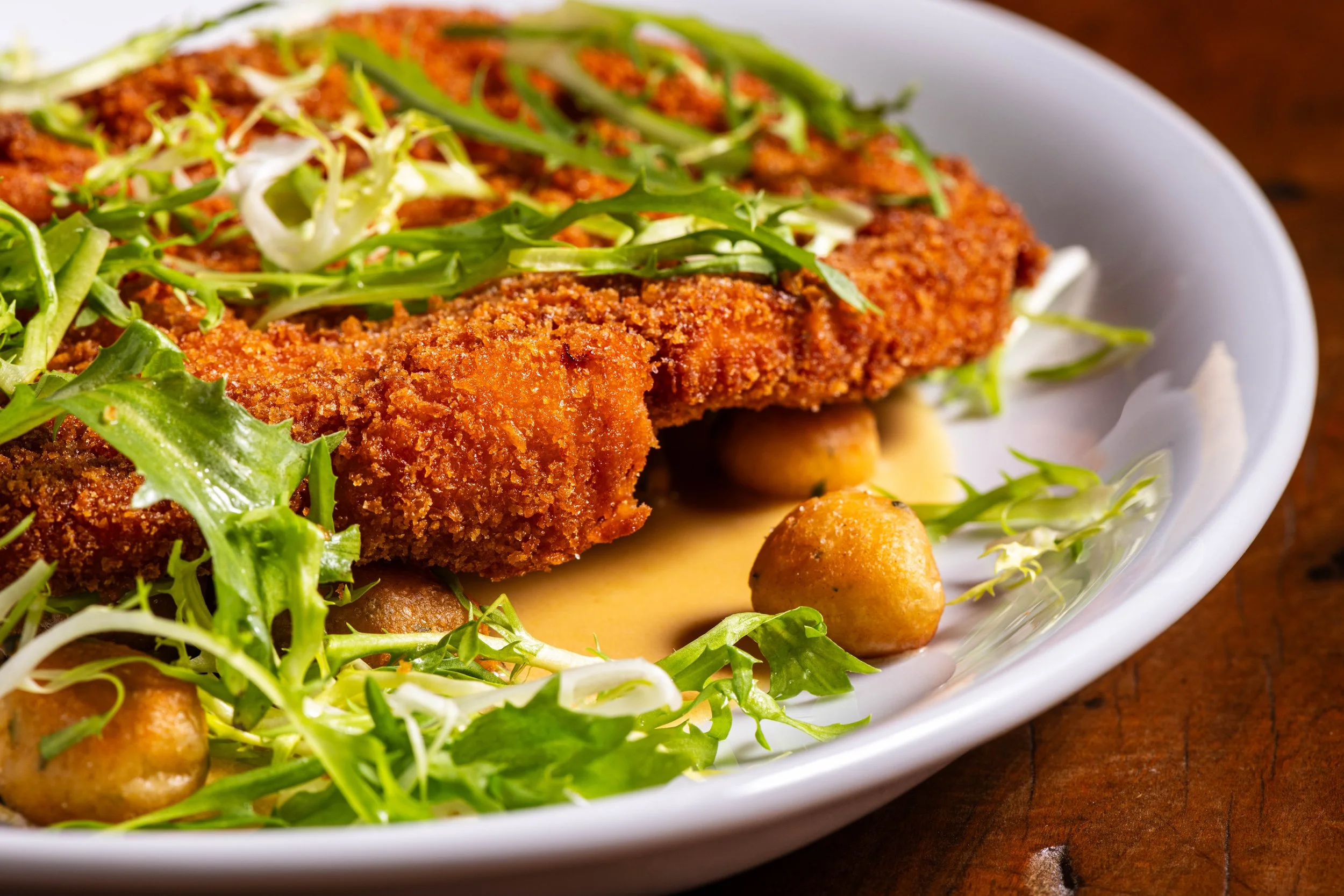A close up of our Chicken Milanese main dish on a white plate.