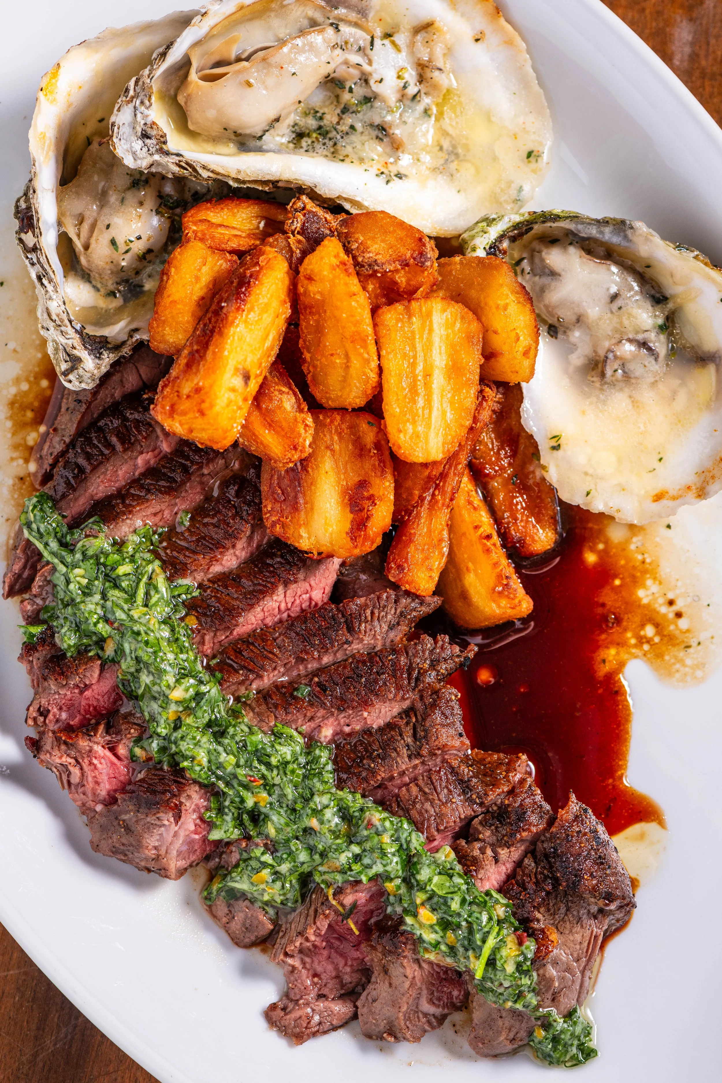 A close up of a steak dish with fried parsnips and broiled oysters. 