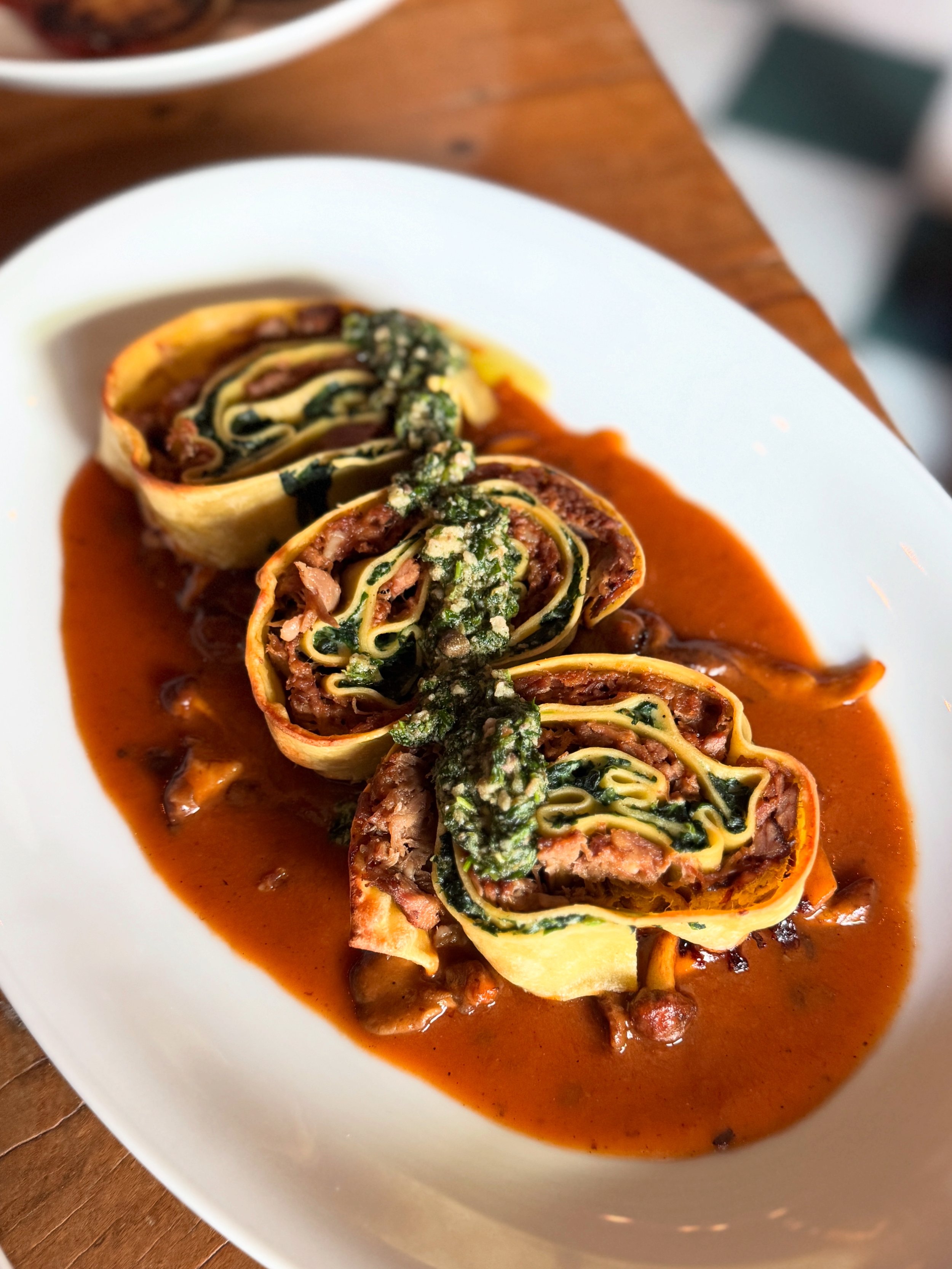 Close-up of a white oval plate with stuffed pasta rotolo on a white, oval plate. 