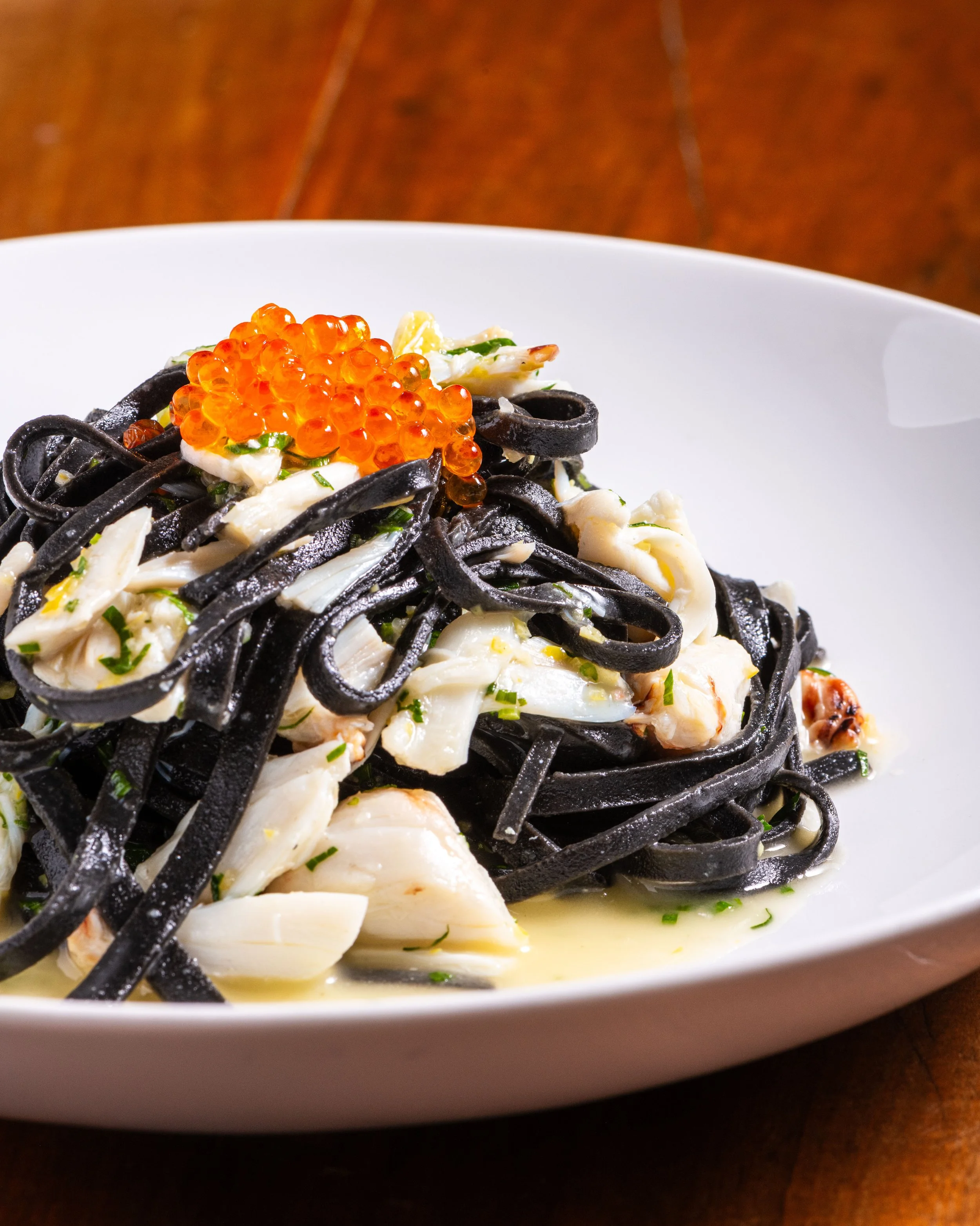 Squick ink Tajarin pasta with crab meat and trout roe on top.