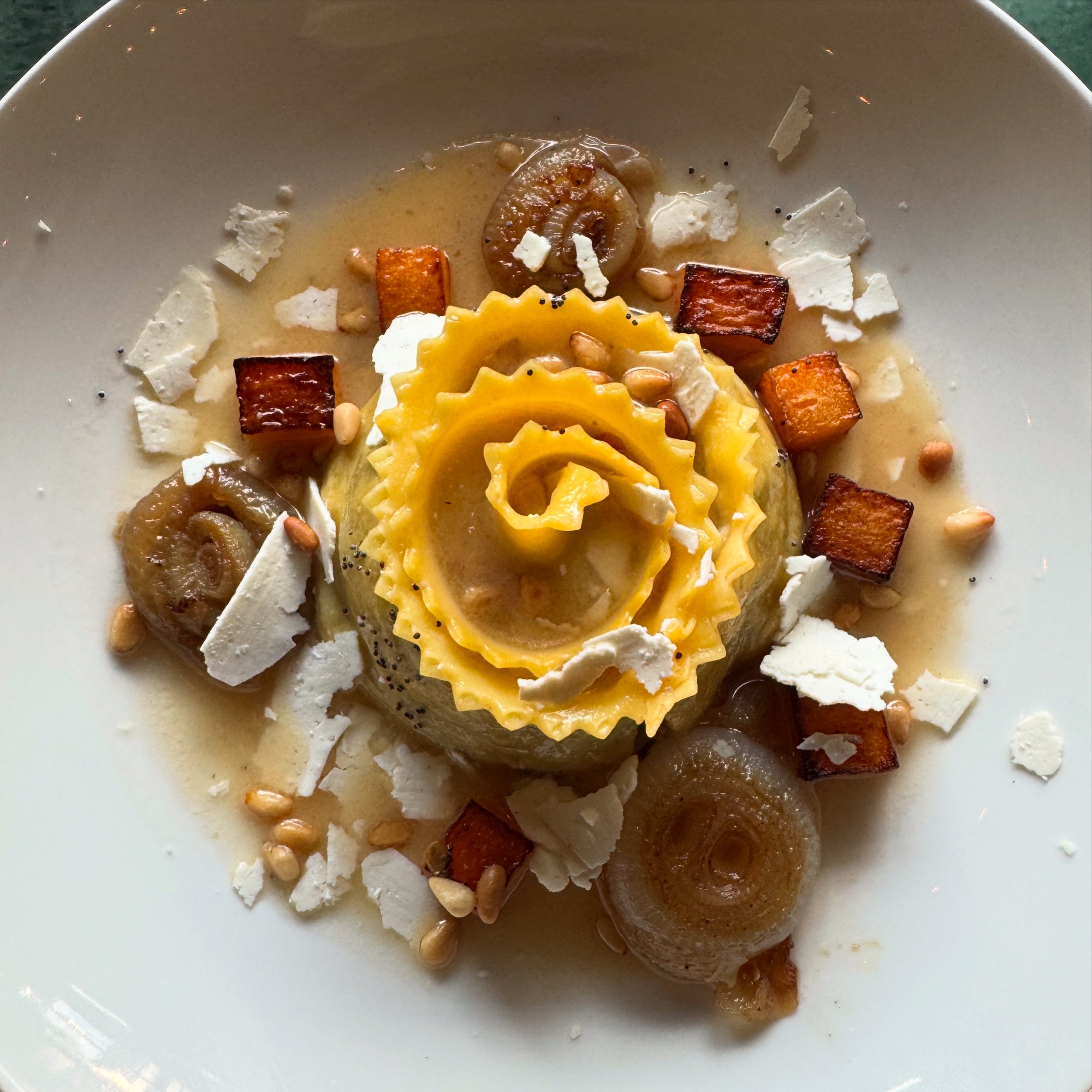A white bowl containing a fresh pasta dish. Stuffed Papardelle.