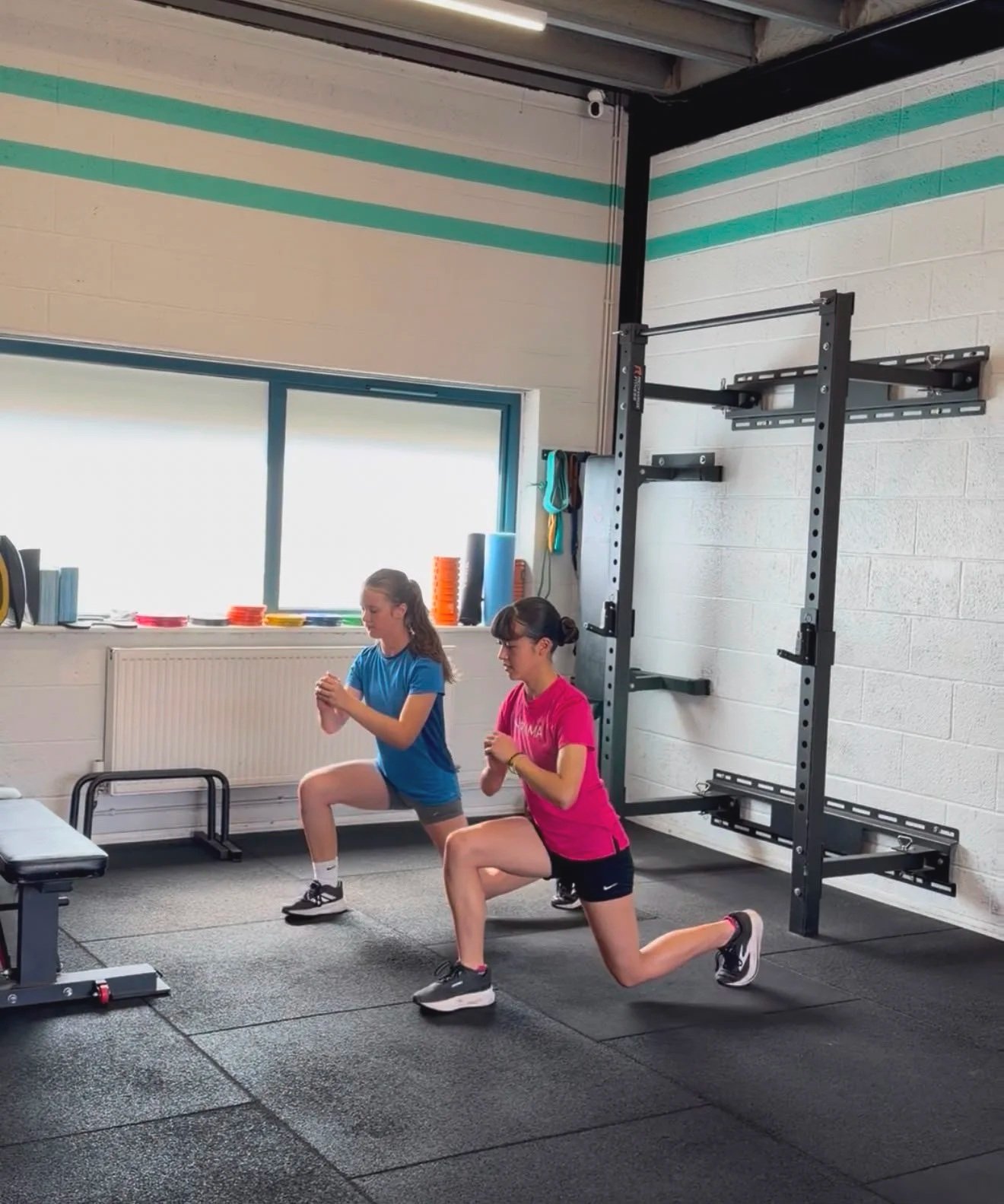 Girls practice lunges amongst gym equipment