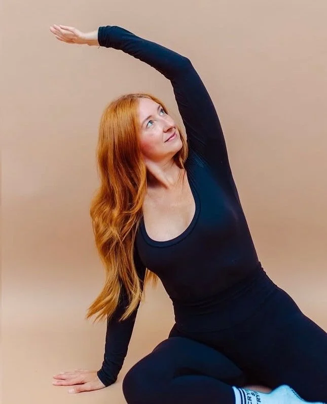 Person in a magenta sweatshirt holding a Dalmatian puppy.