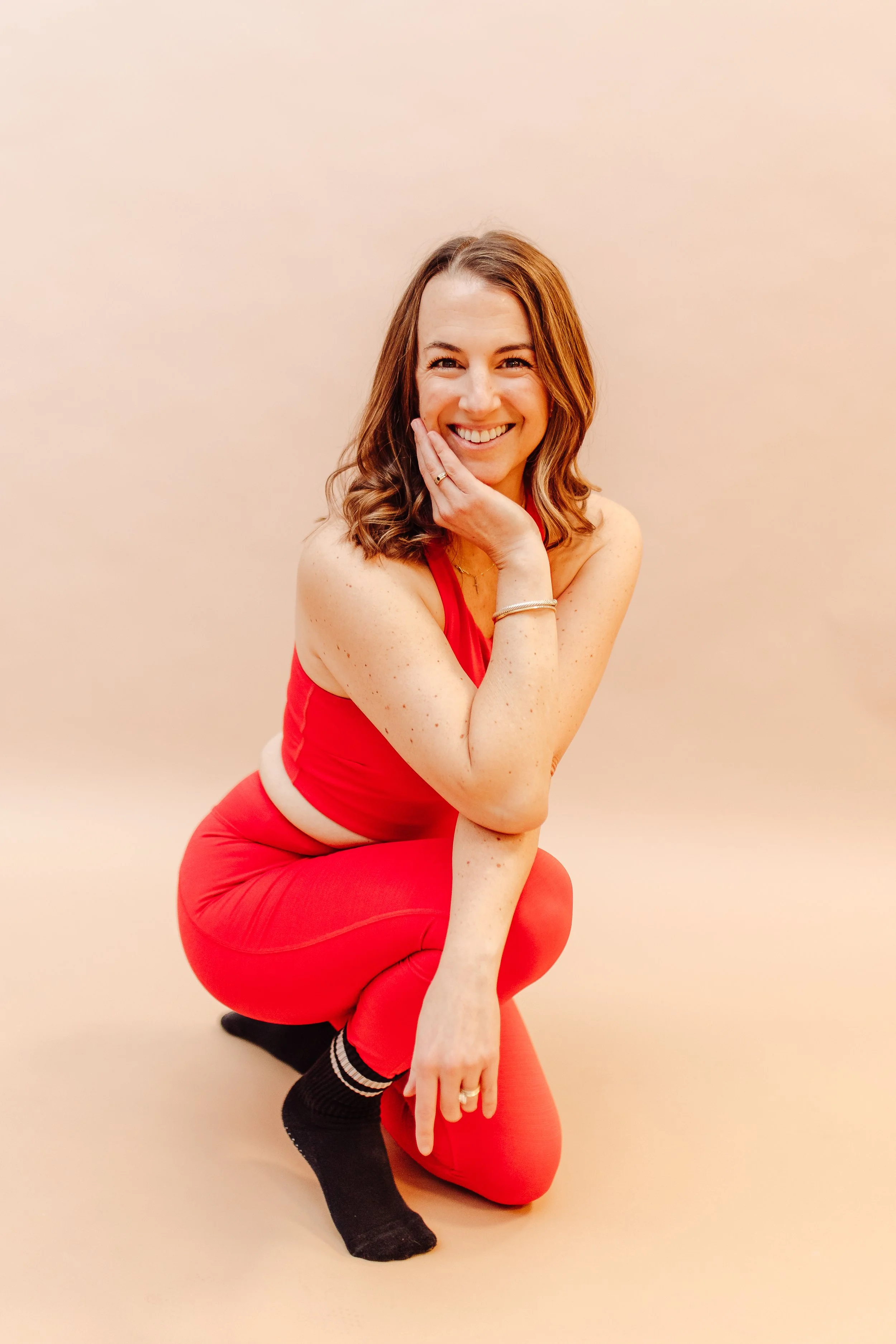 Woman in black top smiling in front of shelves in a room with wooden floor and arched wall niche.