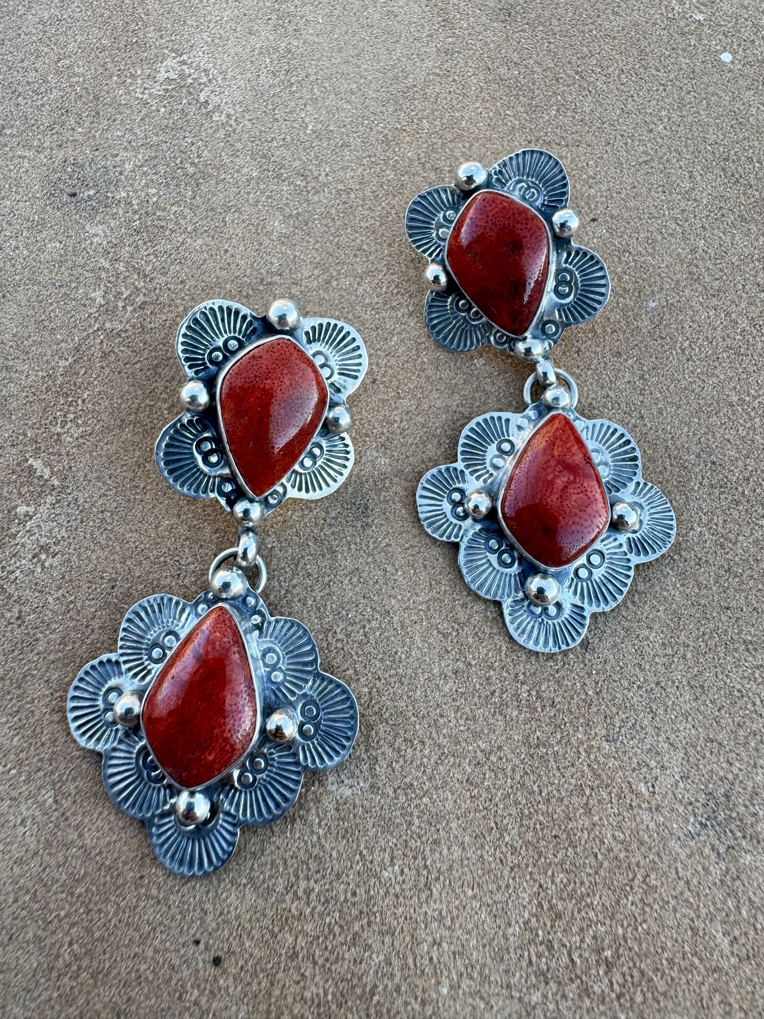 Silver earrings with red stones and intricate floral patterns
