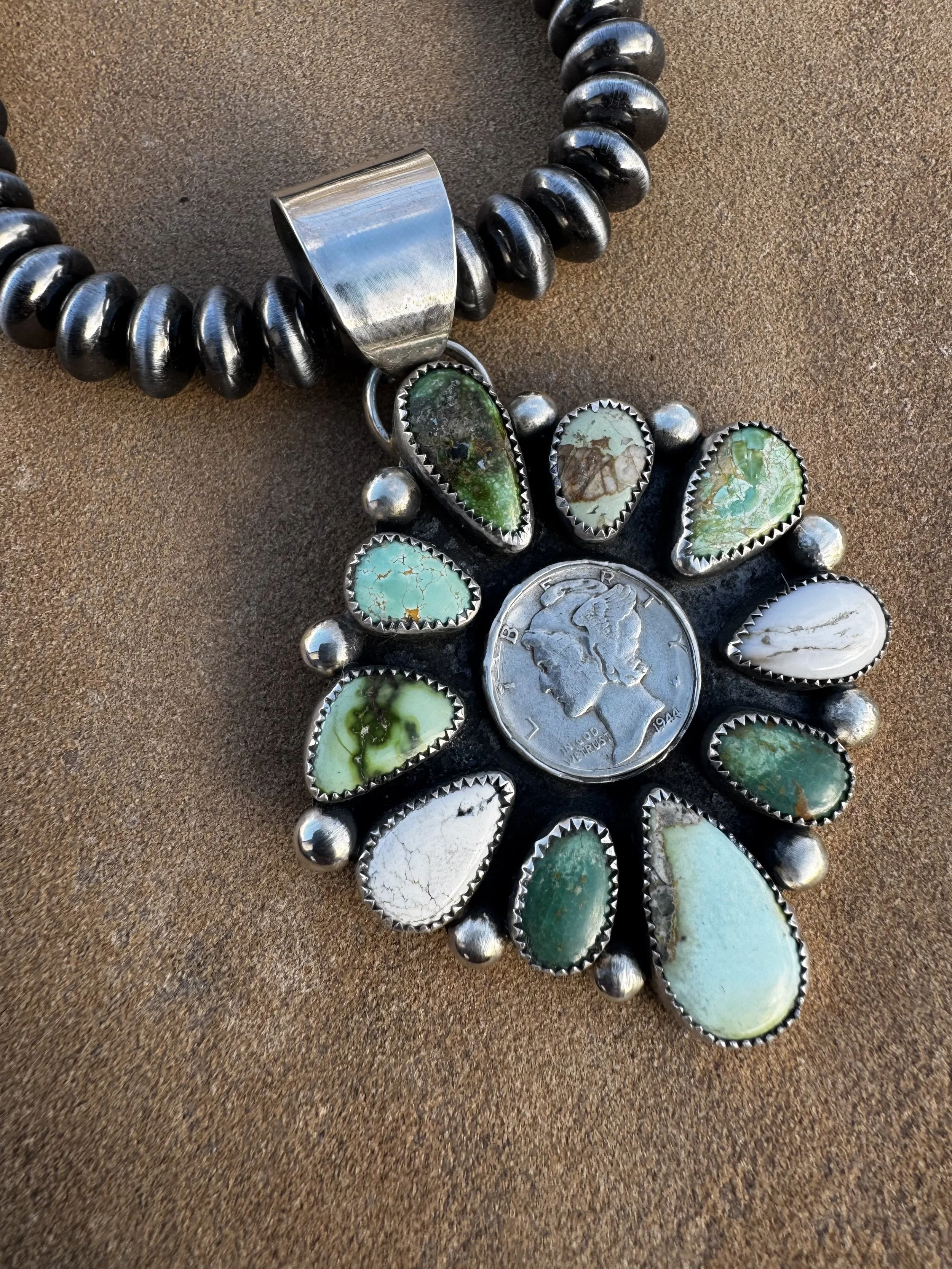 A silver necklace with black beads and a pendant featuring a 1944 Roosevelt dime surrounded by ten teardrop-shaped turquoise and green stones.