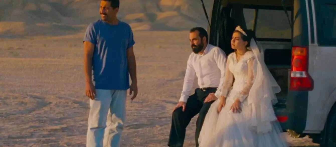 Two men dressed in 19th-century costumes standing outdoors, one holding a book.