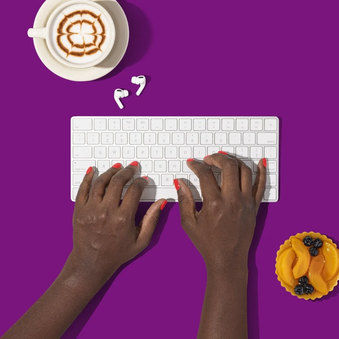 a writer's hands typing on a keyboard with a sweet treat ready and waiting for them