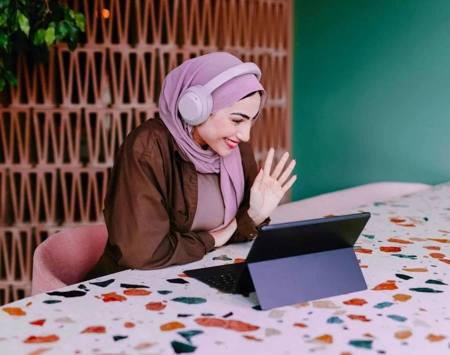 author wearing a hijab smiles and waves at her tablet during a done-with-you branding session