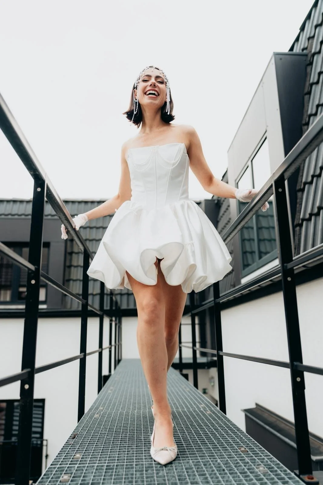 Blonde bride with natural makeup in a white wedding dress and groom in a light suit holding hands while walking down the aisle outdoors during a wedding ceremony.