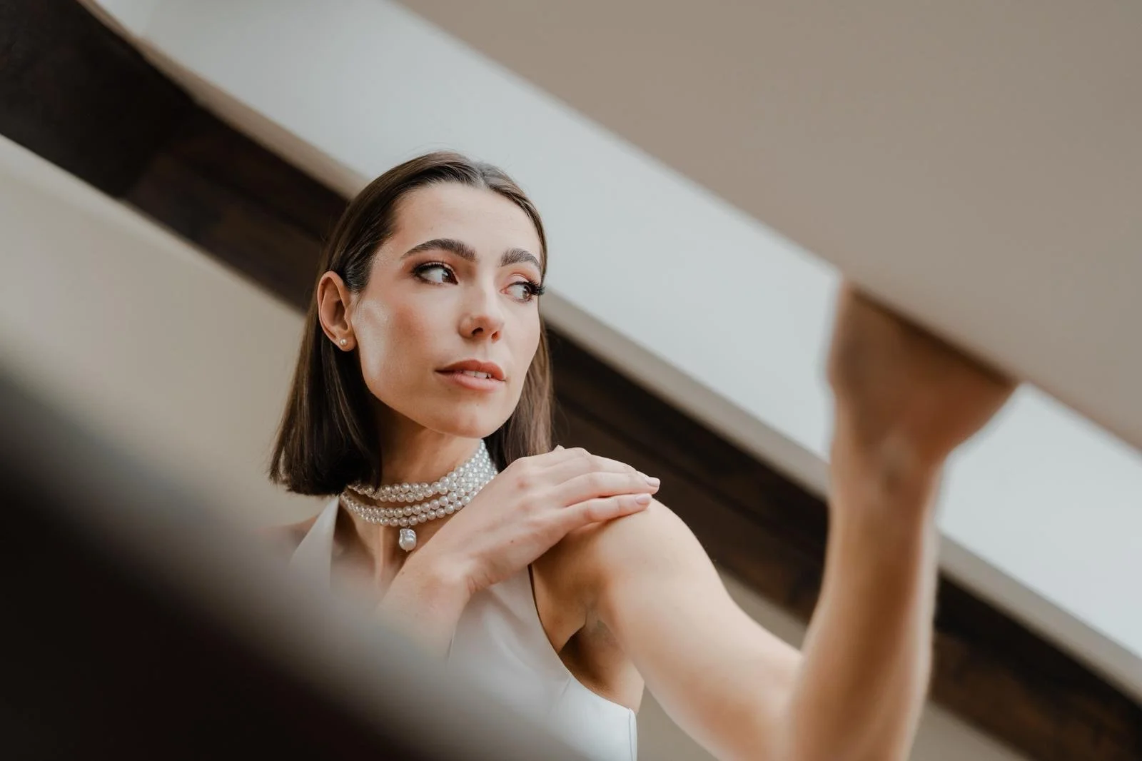 A woman with long blonde hair in a white lace dress smiling in a decorated room with flowers and stained glass windows.