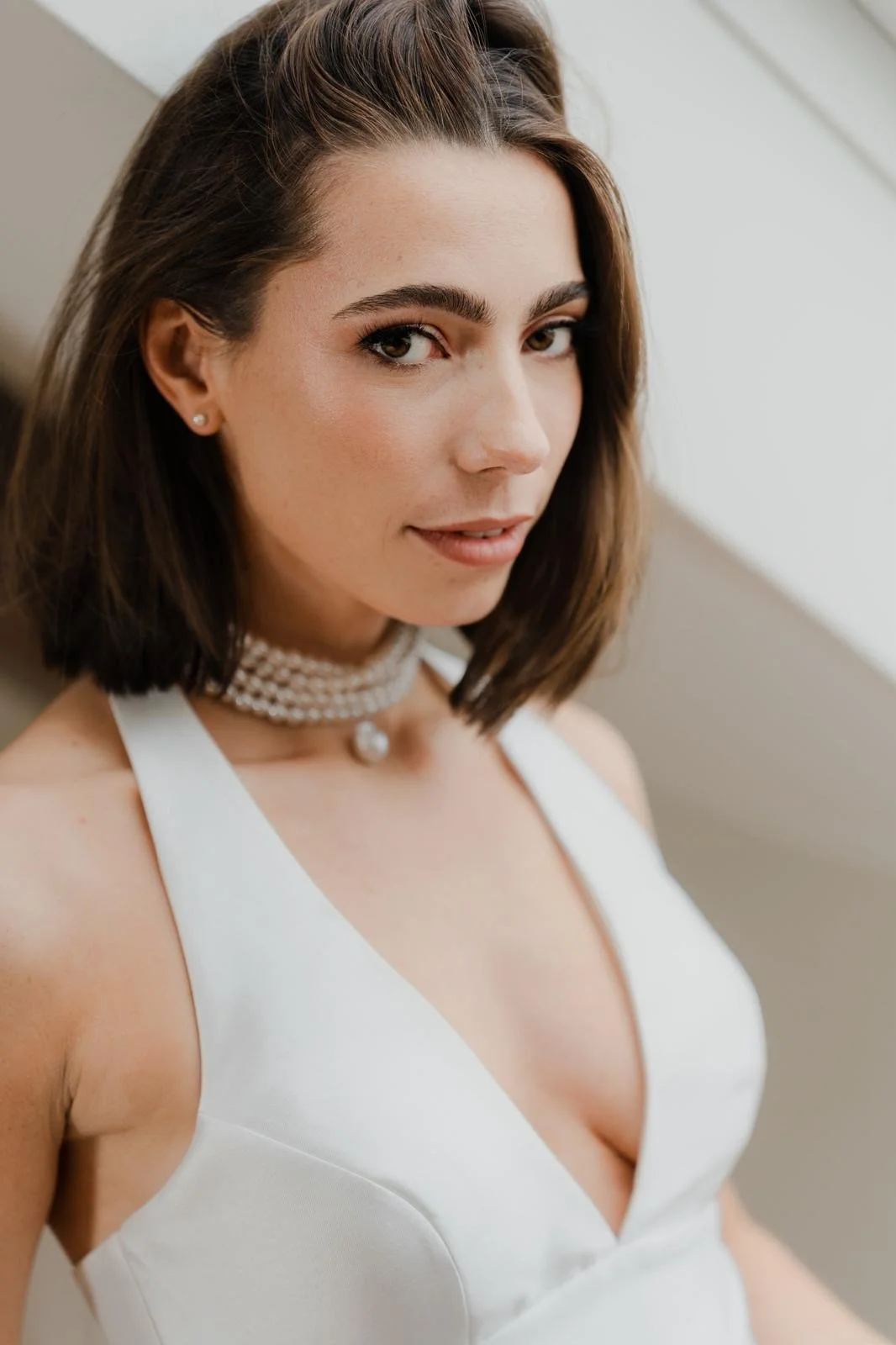 Blonde bride with natural makeup in a white wedding dress and groom in a light suit holding hands while walking down the aisle outdoors during a wedding ceremony.
