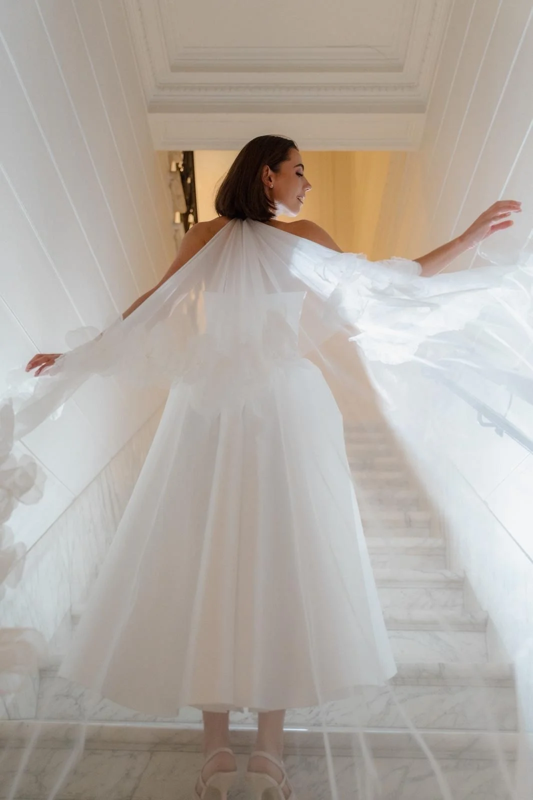 A bride and groom with foreheads touching, smiling, under a veil on the wedding day.
