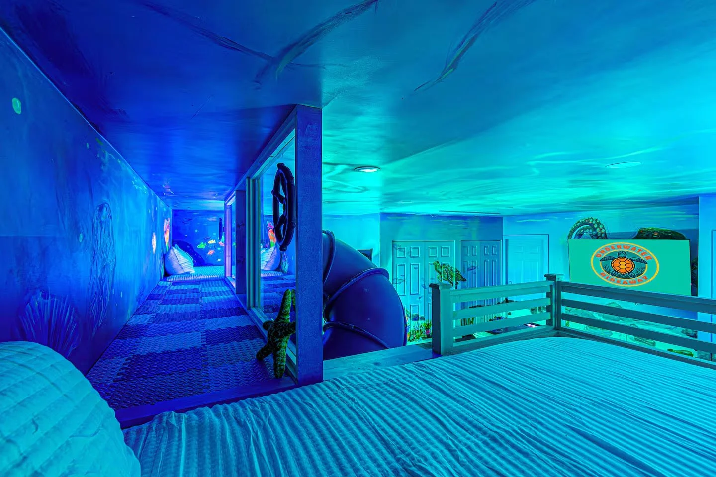 Backyard patio with a swimming pool, inflatable swan and ring, outdoor sectional with pillows, fire pit, hanging chair, potted plants, and privacy fence.