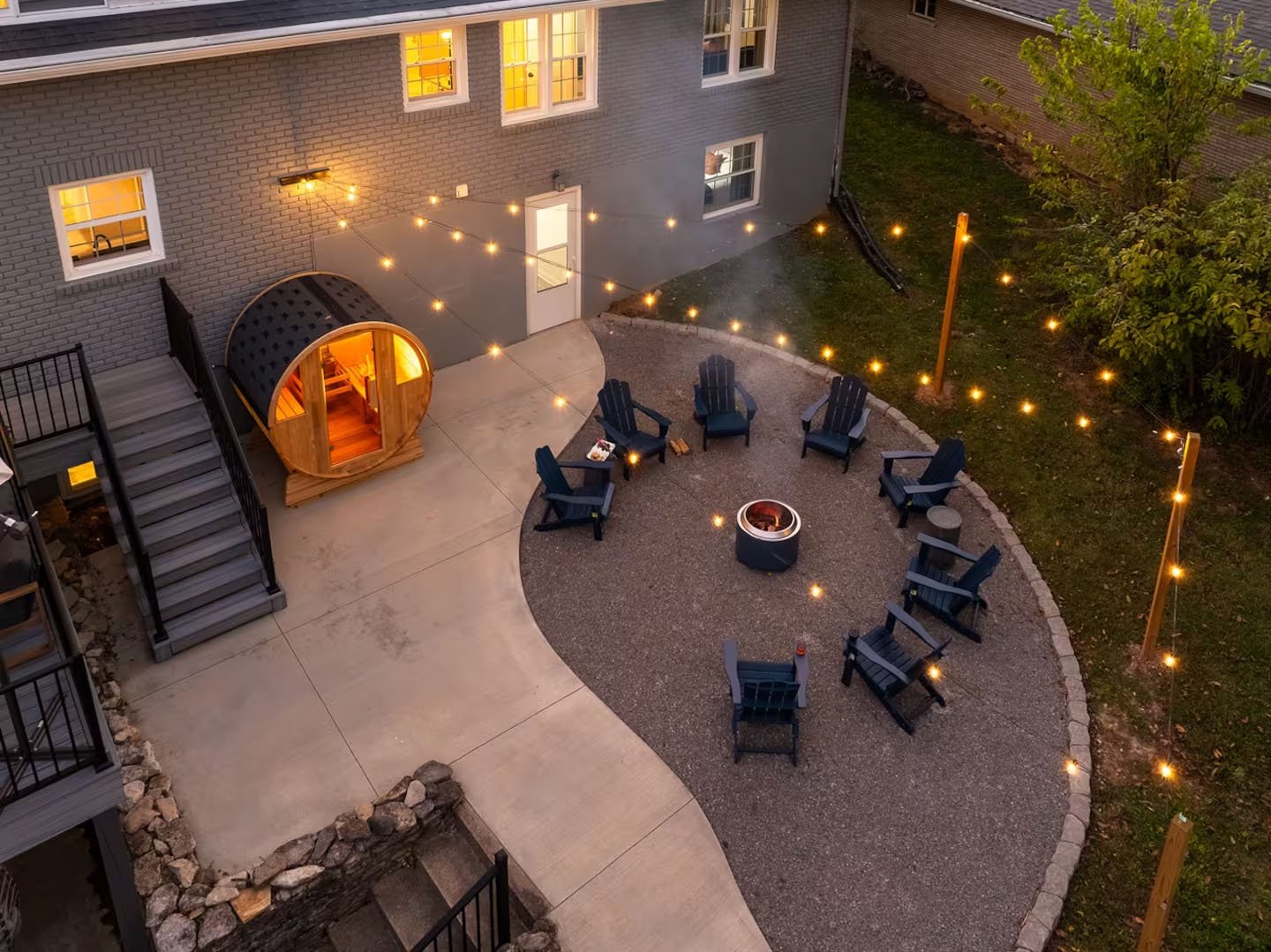 Interior of a living space featuring a kitchen and a spiral staircase, with a stone fireplace, a mounted deer head, a wall-mounted television, and various furnishings.