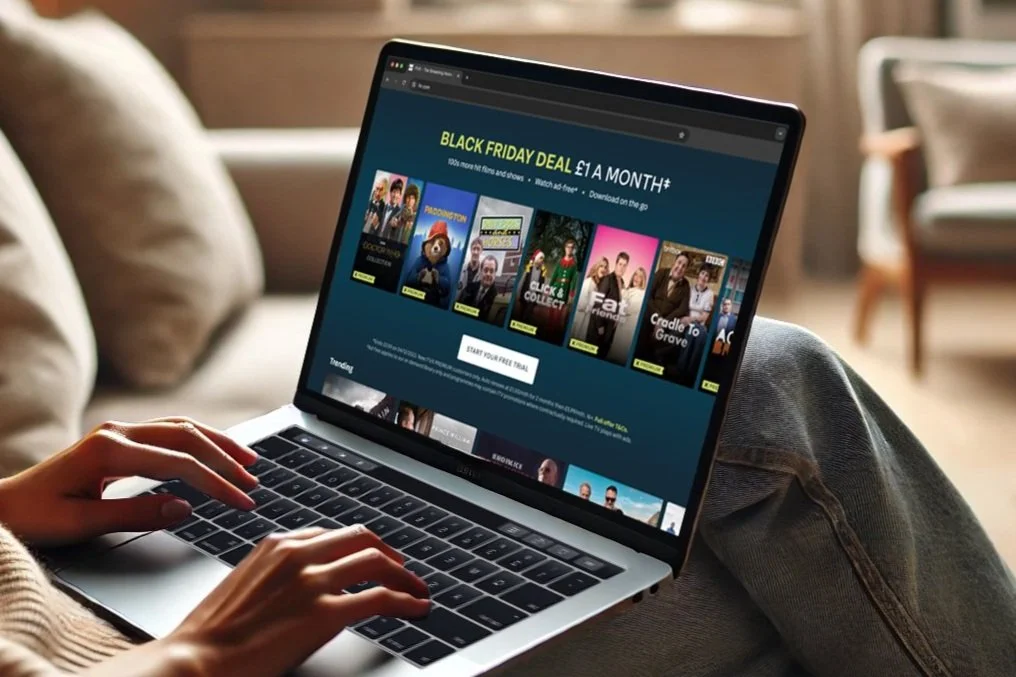 Figure sitting on sofa with open laptop on their lap with a Black Friday deal displayed within a rail of the ITVX website