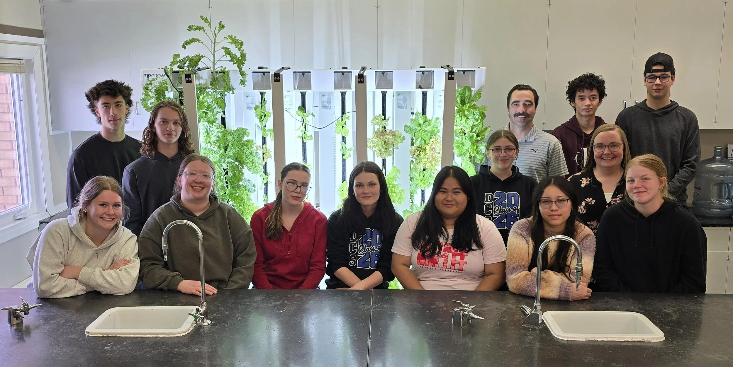 Students at Dinsmore Composite School sit in front of their tower garden, accompanied by MP Jeremy Patzer.