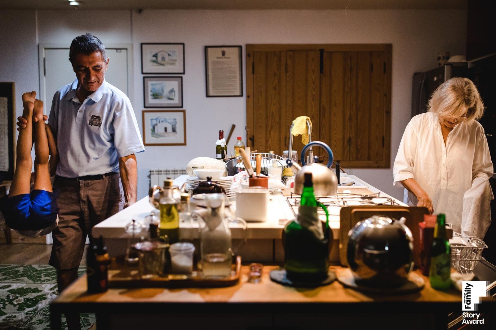 kitchen scene where grandfather is holding a little girl upside down while putitng on the table